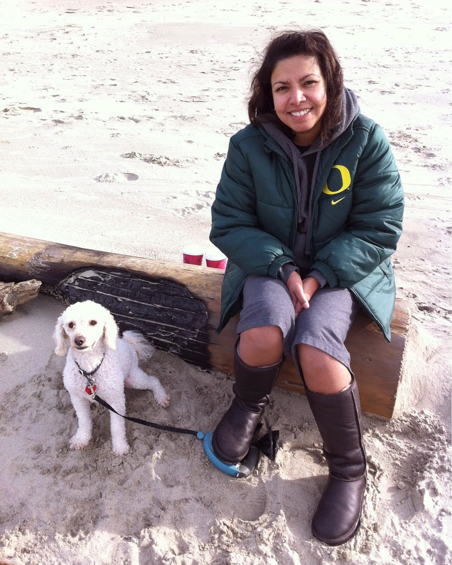 Dr. Huma Pierce sitting on a bench at the beach with her dog